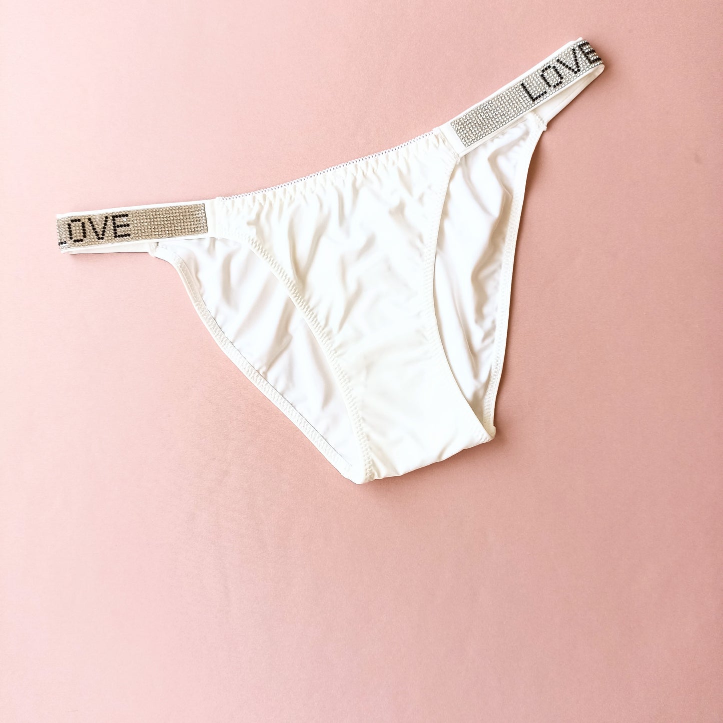 Lygios kelnaitės stringai su blizgiais šoneliais "LOVE", pieno balta, kūno (L-XL)